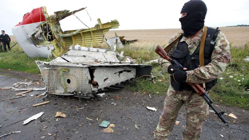 An armed militant by a part of the wreckage of MH17 Photo Maxim Zmeyev, Reuters
