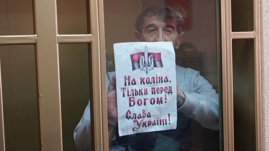 Oleh Prykhodko with a sign reading: On my knees only before God. Glory to Ukraine. In court on 9.06.2020 Photo Crimean Solidarity